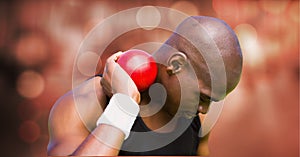 African american man practicing shot put against spots of light on red background