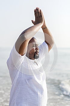 African American man practicing yoga at the beach