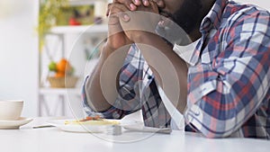 African american man praying before eating, asking god to bless food, faith