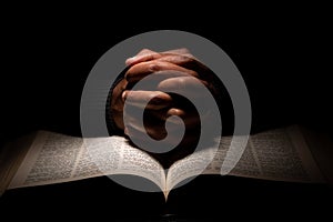 African American Man Praying with Hands on Top of the Bible