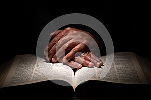 African American Man Praying with Hands on Top of the Bible