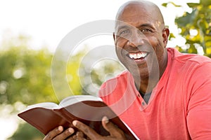 African American man praying and reading the Bible.