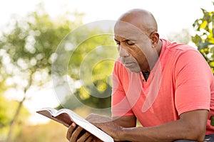 African American man praying and reading the Bible.