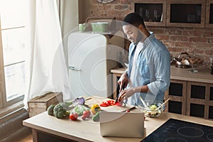 African-american man preparing salad in loft kitchen
