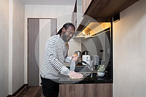 African American man in rubber gloves wipe dust from table in kitchen, Housework, cleaning, lifestyle, household