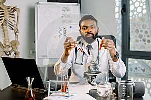 African-american man scientist doctor working in lab making medical research, using laboratory tools, microscope, test