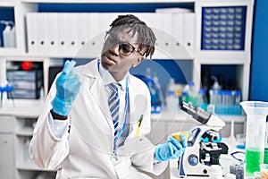 African american man scientist holding pill and lemon at laboratory