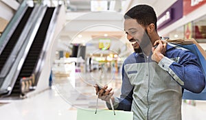 African american man with shopping bags using cellphone