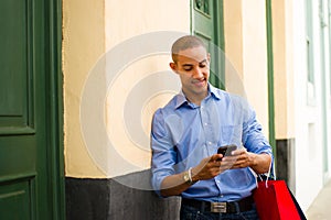 African American Man Shopping And Text Messaging On Phone