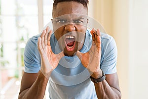 African american man shouting with rage, yelling excited with hand on mouth