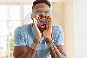 African american man shouting with rage, yelling excited with hand on mouth