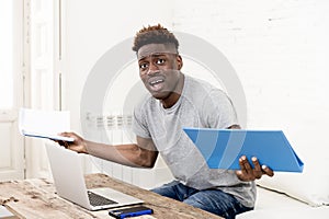 African american man sitting at home living room working with laptop computer and paperwork