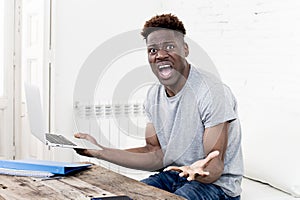 African american man sitting at home living room working with laptop computer and paperwork