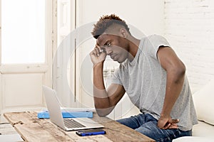 African american man sitting at home living room working with laptop computer and paperwork