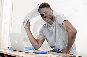 African american man sitting at home living room working with laptop computer and paperwork