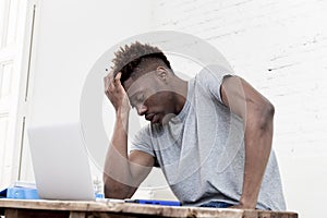 African american man sitting at home living room working with laptop computer and paperwork