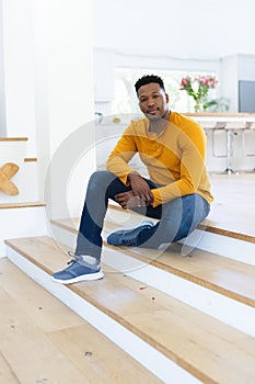 African american man sitting on stairs at home, copy space