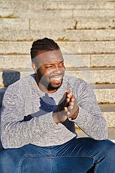 African American man sitting on the stairs smiling on a sunny day. Happy young Latino man. Concept of happiness