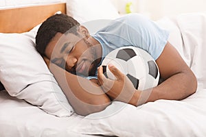 African-american man sleeping and embracing soccer ball