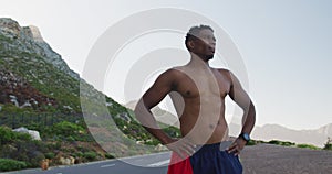 African american man standing and flexing his muscles on a coastal road