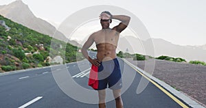 African american man standing and flexing his muscles on a coastal road