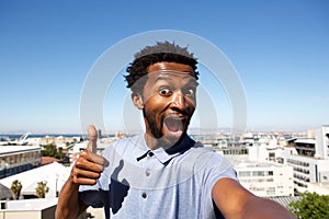 African american man standing by urban background with thumb up