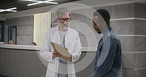 African American man stands with doctor in clinic lobby