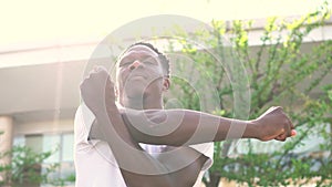 African American man stretching arms in the city street. Young male fitness guy doing warm up in the morning