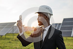 African american man in suit holding bulb at solar station