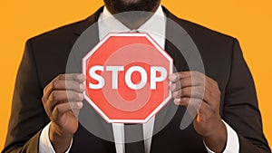 African-American man in suit showing stop sign into camera, work racism protest