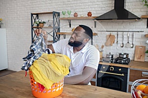 African american man taking out a checkered shirt and looking unpleased