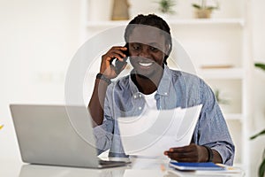 African American Man Talking On Cellphone And Working With Papers At Office