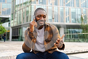 African american man talking on smartphone on street in city outdoor. Man with cell phone chatting with friends. Smiling