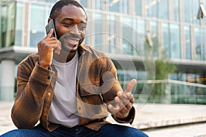 African american man talking on smartphone on street in city outdoor. Man with cell phone chatting with friends. Smiling