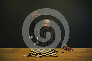 an African American man throws checkers on a table and playing board.