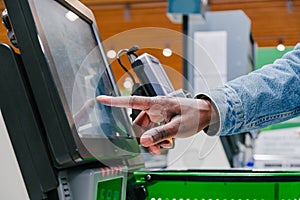 African-American man touches screen of self-checkout point