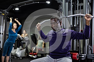 African-american man training on lat pull down machine in gym