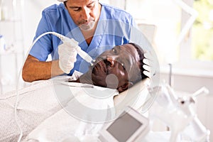 African american man undergoing radiofrequency facial tightening procedure