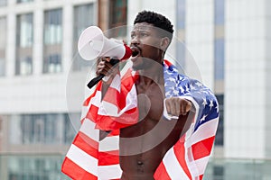 African american man with usa flag protests and shouts into a megaphone shows aggression on white, activist guy on strike, black