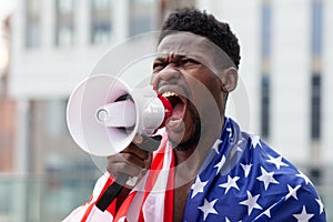 African american man with usa flag protests and shouts into a megaphone shows aggression on white, activist guy on strike, black