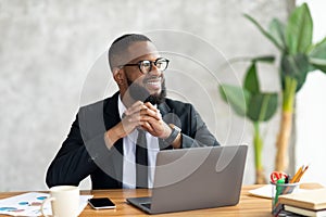 African American man using laptop thinking looking away