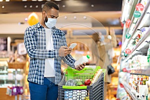 African American Man Using Mobile Phone Scanning Product In Supermarket