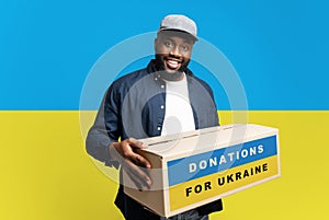 African-American man volunteer giving help box with Ukrainian flag to refugee photo
