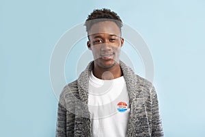 African american Man with Vote button pinned on his t-shirt on blue