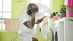 African american man washing clothes holding dirty t shirt at laundry room