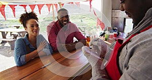 African american man wearing apron taking order from a couple at the food truck