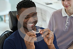 African American man wearing clear braces in order to get rid of malocclusion