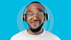 African American Man Wearing Headphones Listening To Music, Blue Background