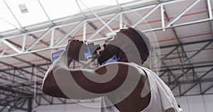 African american man wearing lowered face mask drinking at gym