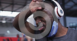 African american man wearing lowered face mask exercising at gym